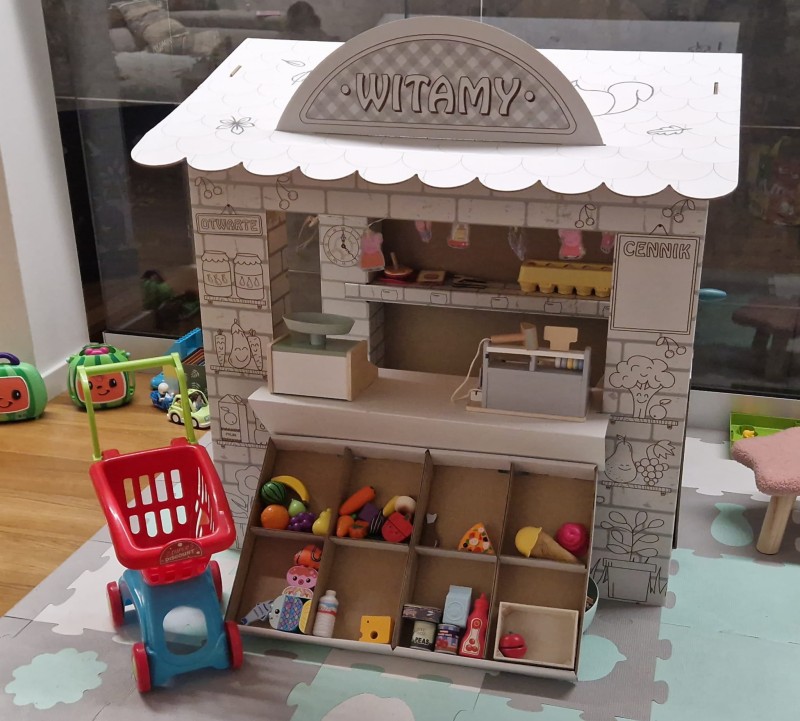 Duży sklep kolorowanka z tektury 5-warstwowej przestronna konstrukcja. Z otwieranymi drzwiami i oknami, ladą i półkami. Zapewnia kreatywną i bezpieczną rozrywkę dla dzieci. Nadrukowane owoce, warzywa.