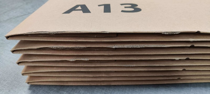 Solidny karton o wymiarach 400x300x200mm, wykonany z szarej 5-warstwowej tektury. Pudełko posiada automatyczne dno, dwa paski klejowe, zrywkę i nadruk A13 na boku. Tektura delikatnie pęka przy składaniu.